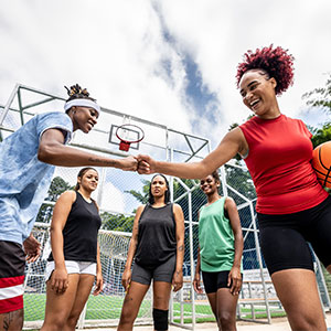 Group of women's basketball players on the court. Two players smile and fist-bump.